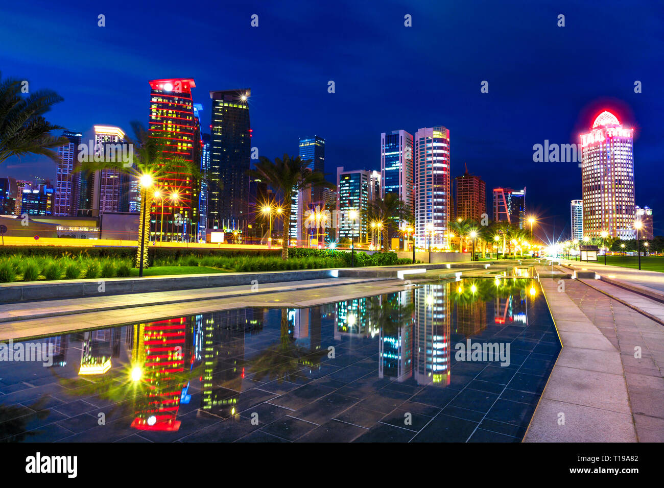 Doha West Bay high rises at night reflecting in the water of downtown park. Lighting skyscrapers of Doha skyline in Qatar, Middle East, Arabian Stock Photo