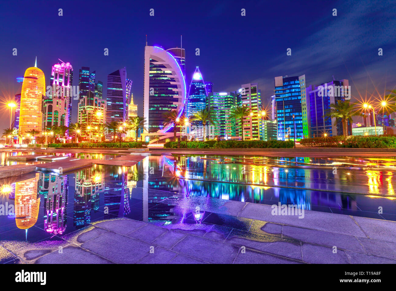 Capital of Qatar. Colorful Doha West Bay high rises illuminated at night reflections in downtown park. Scenic towers of Doha skyline, Middle East Stock Photo