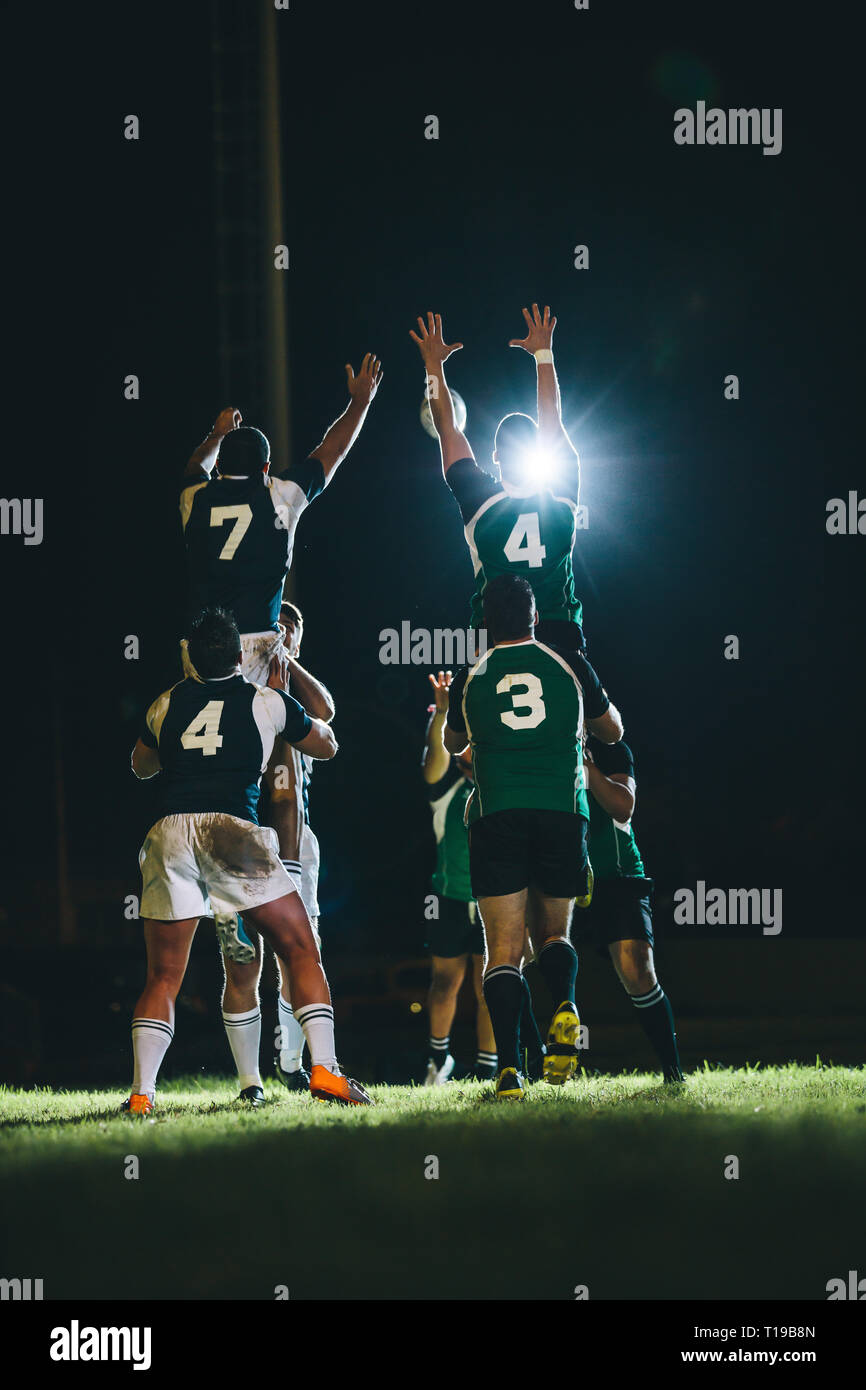 rugby players jumping for line out at the stadium. Teams jumping for possession of the ball during rugby match. Stock Photo