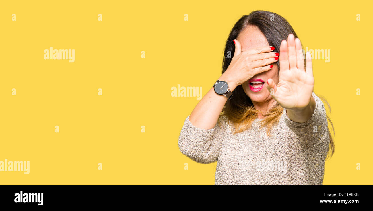 Beautiful middle age woman wearing fashion sweater covering eyes with hands and doing stop gesture with sad and fear expression. Embarrassed and negat Stock Photo