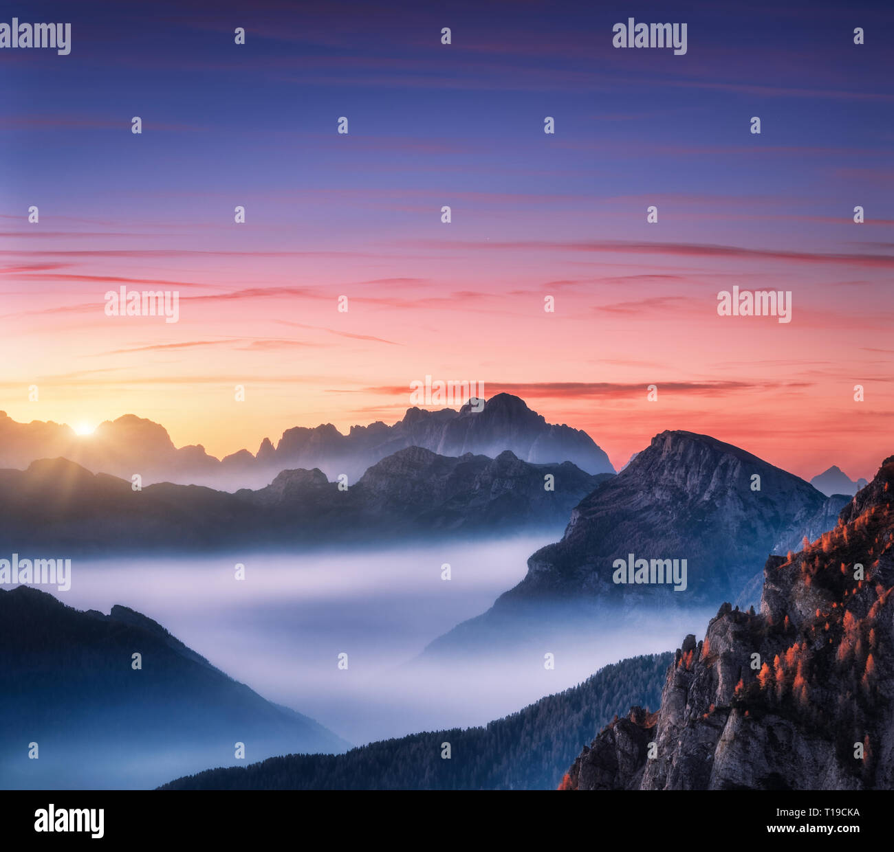 Mountains in fog at beautiful sunset in autumn in Dolomites, Italy