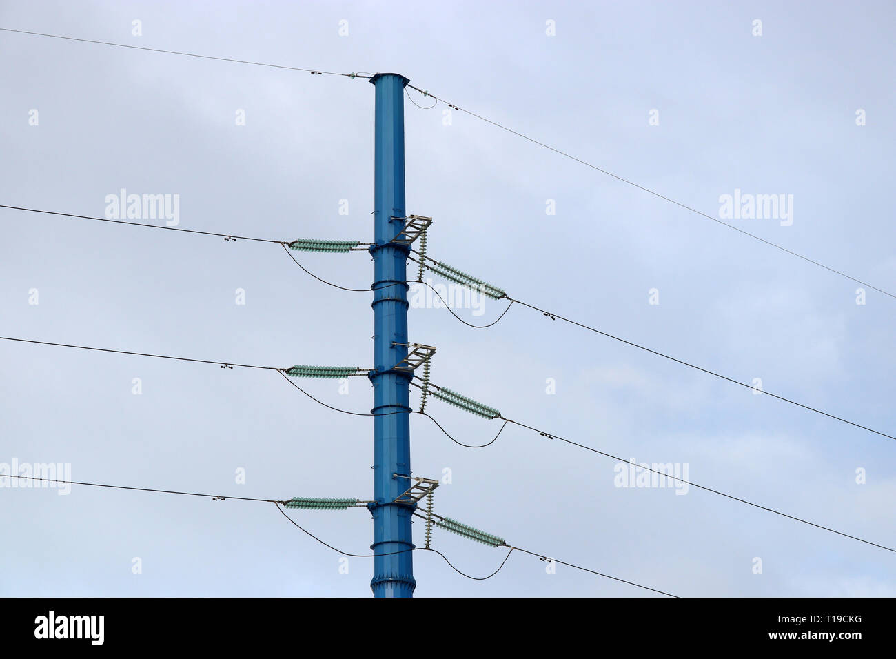Power line support against blue sky with white clouds. High-voltage electricity transmission line Stock Photo