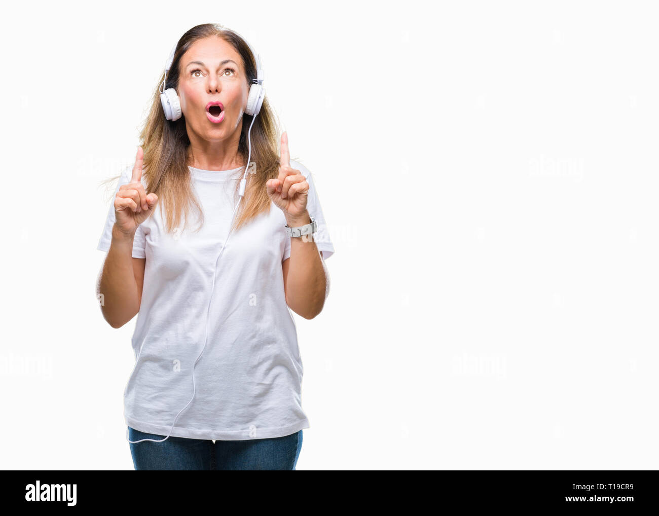 Middle age hispanic woman listening to music wearing headphones over ...