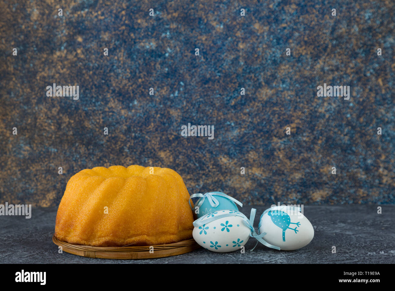 Easter bread and blue Easter eggs on dark stone table Stock Photo