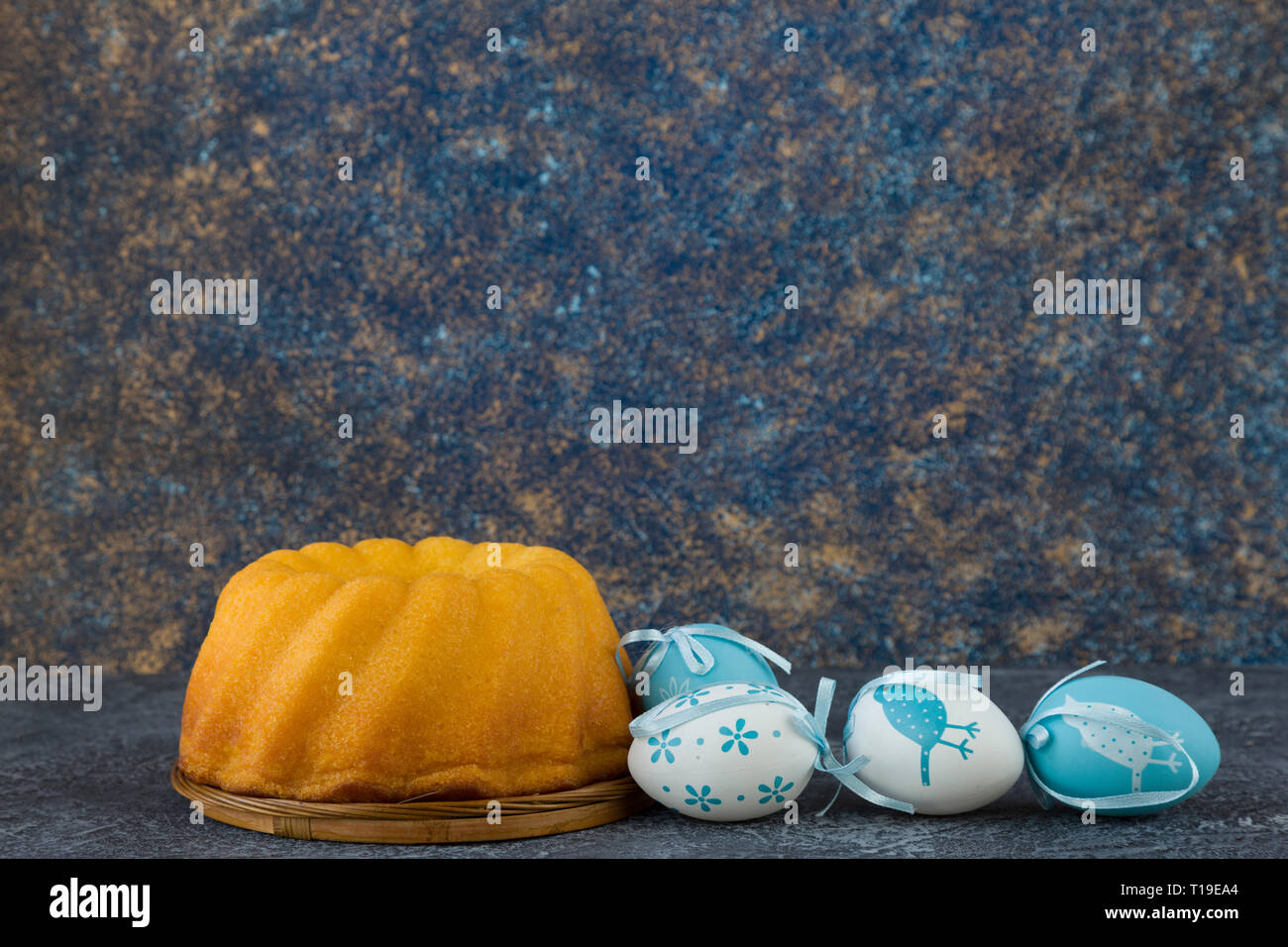 Easter bread and blue Easter eggs on dark stone table Stock Photo