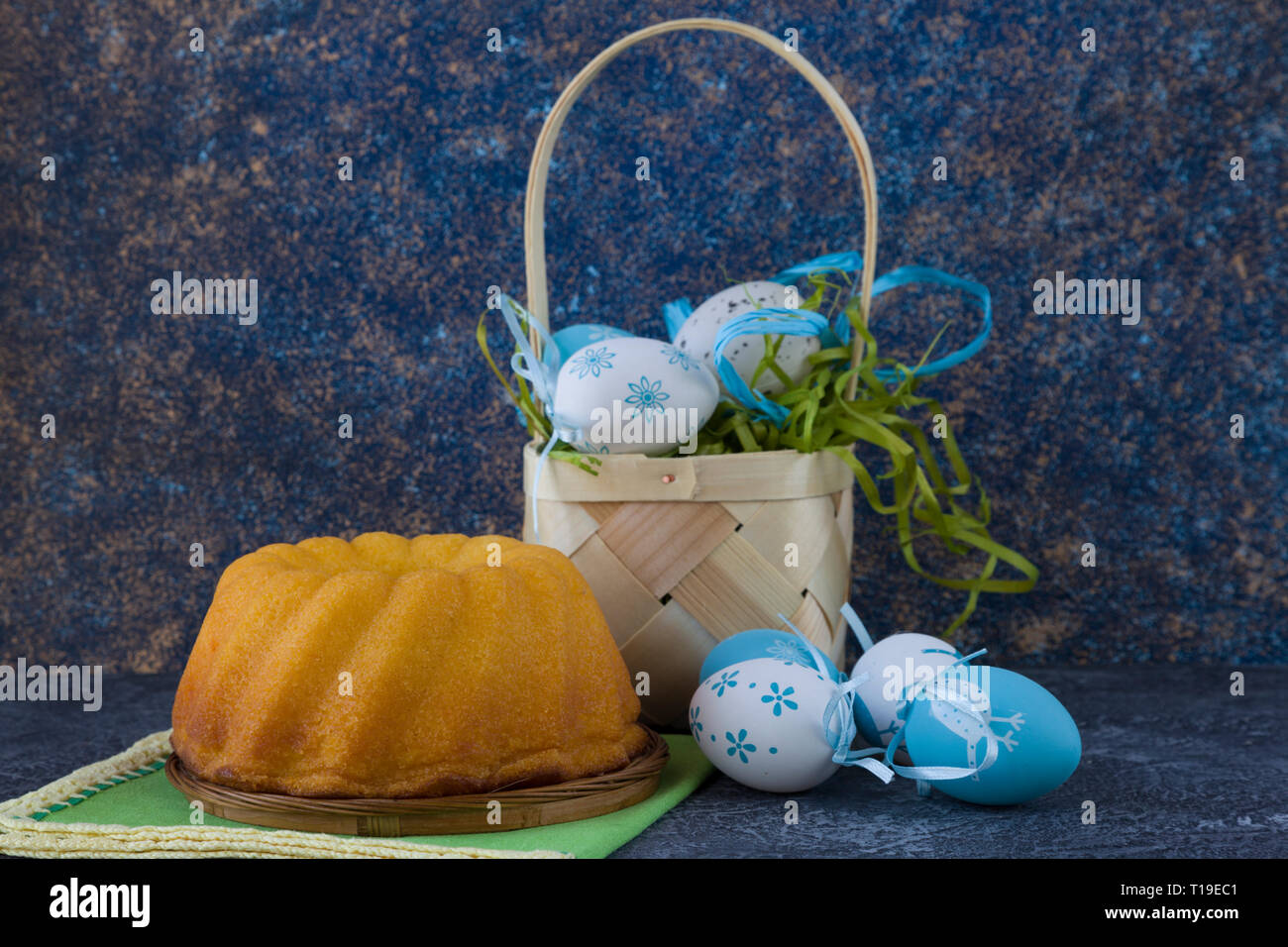 Easter bread and painted Easter eggs in a basket on dark stone table Stock Photo