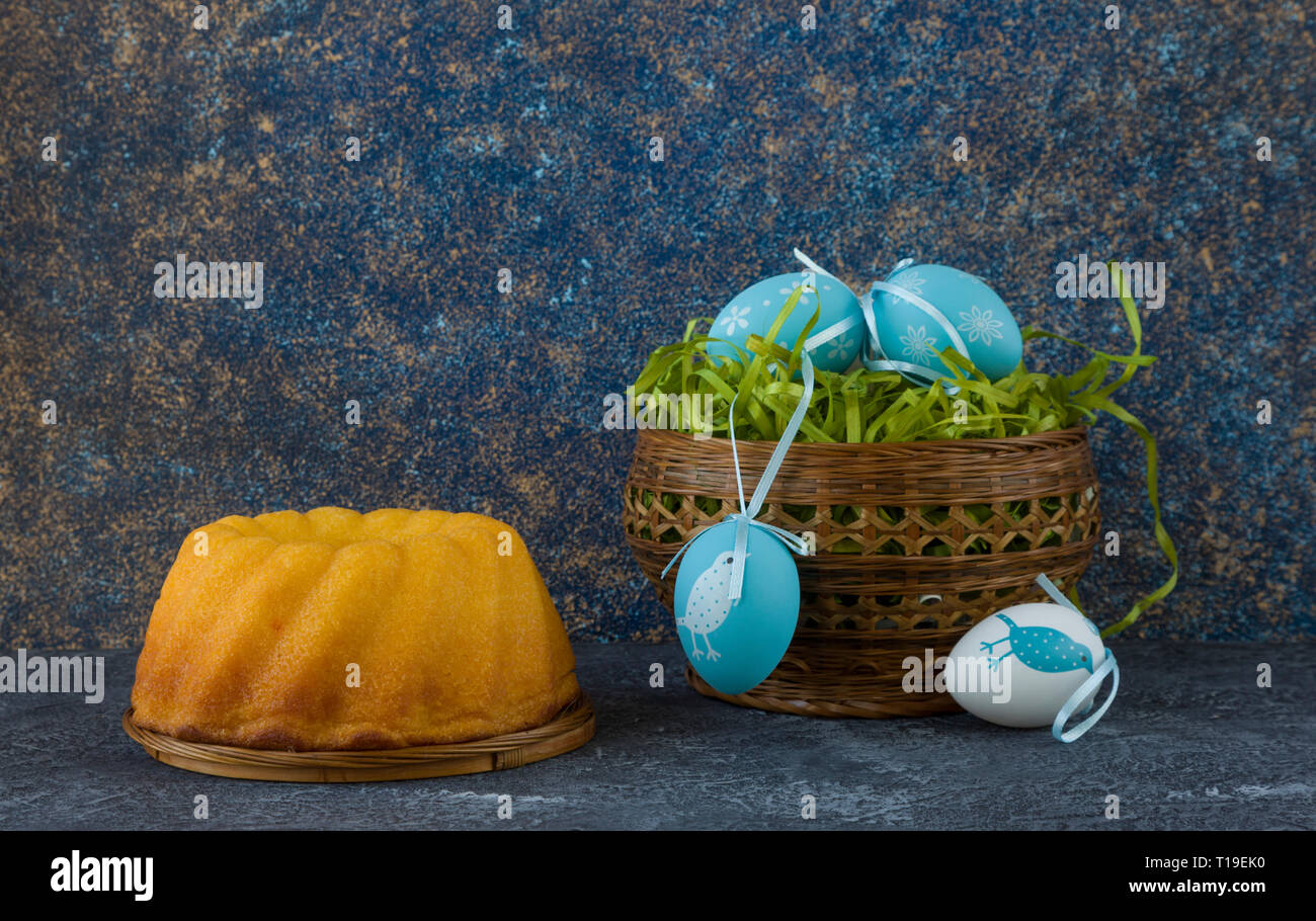 Easter bread and painted Easter eggs in a basket on dark stone table Stock Photo
