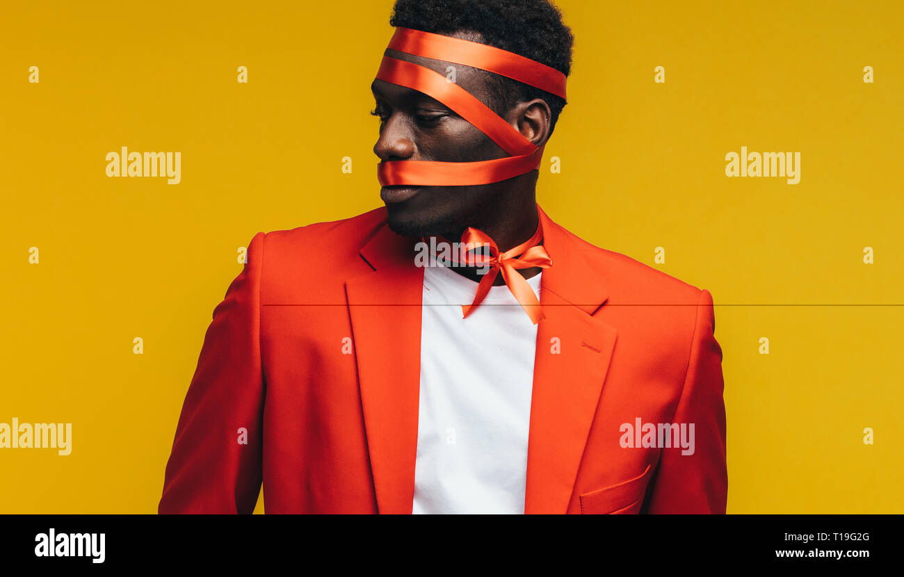 Man With Ribbon African man with satin ribbon wrapped on his face against yellow ...