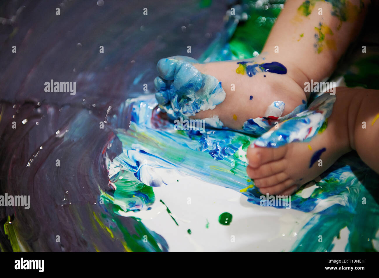 Small baby feet with blue paint on wet canvas Stock Photo