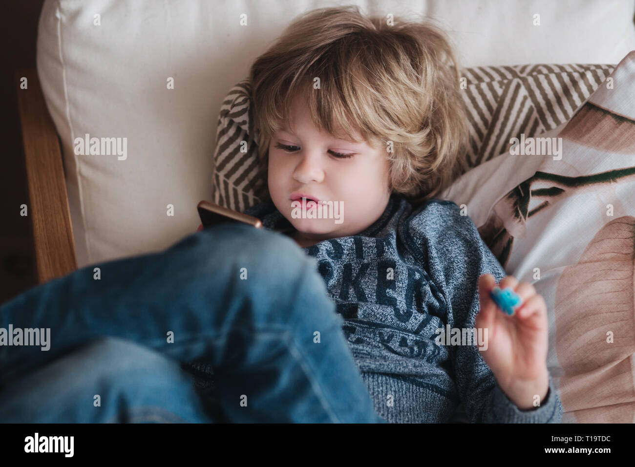 Little cute boy play online game at mobile phone at home. Addiction concept Stock Photo