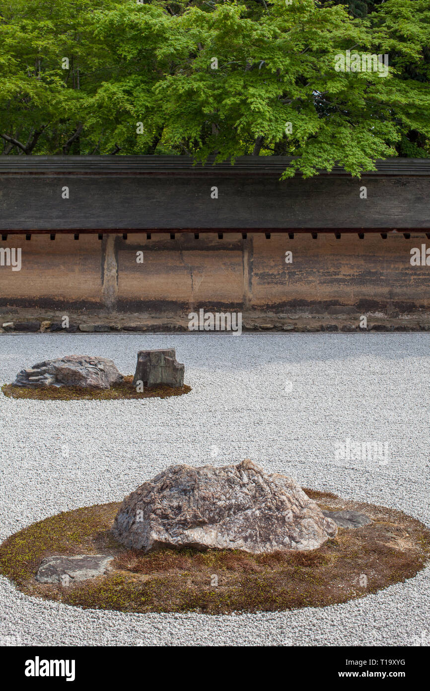 A portion of the Zen rock garden, earthen wall, and trees at Ryōan-ji in Kyoto Stock Photo