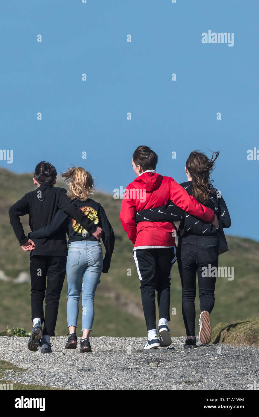 Young teenagers with their arms around each other walking along a footpath; Stock Photo