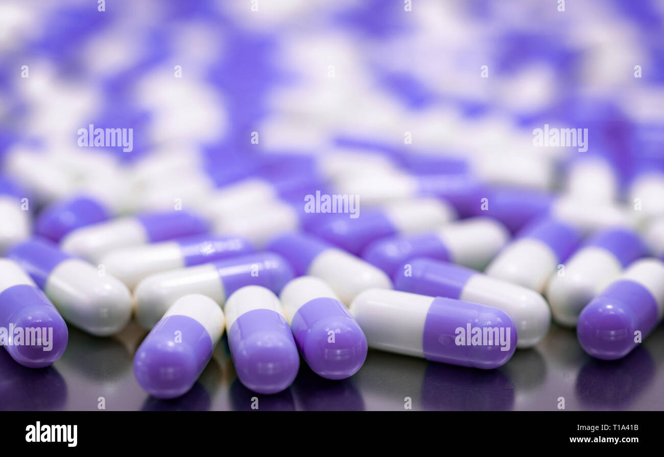 Selective focus purple and white capsule pills on stainless steel drug tray. Pile of capsule pills. Pharmaceutical industry. Pharmacy product. Global  Stock Photo