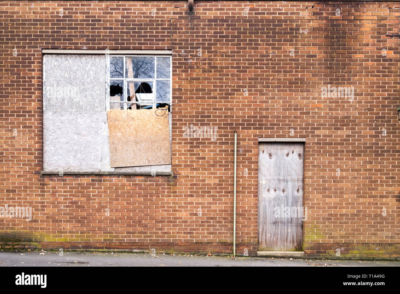 Old brick building with boarded up and broken windows and door, in Consett, County Durham, UK