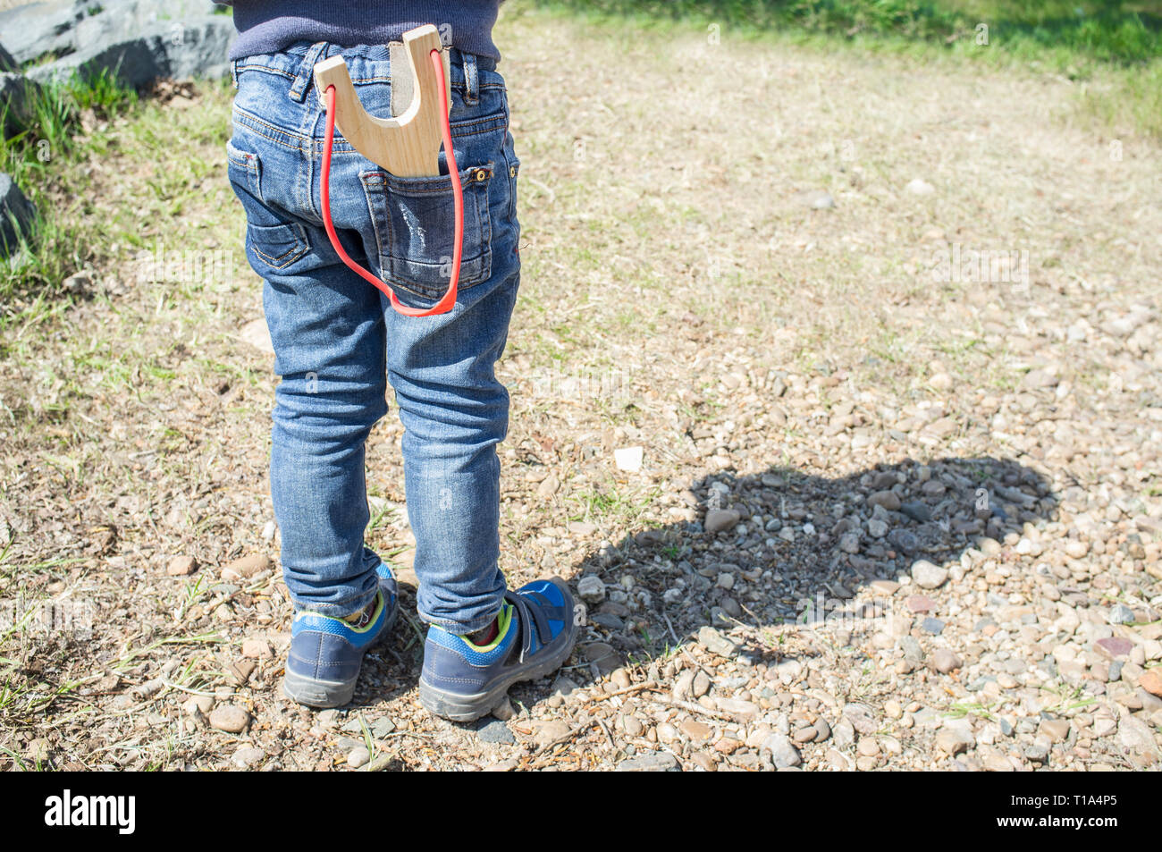 3 years little boy with slingshot in the jeans pocket. Enjoy toy in nature concept Stock Photo