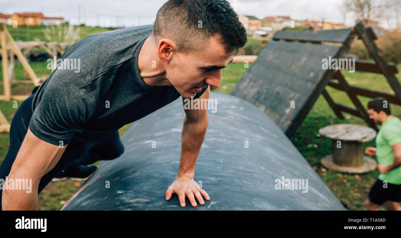 Man in an obstacle course climbing a drum Stock Photo