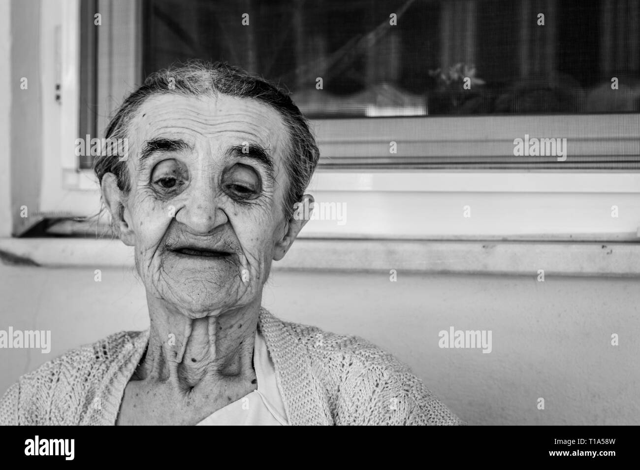 Black and white portrait of an elderly Turkish woman in pajamas sitting in the balcony. Stock Photo