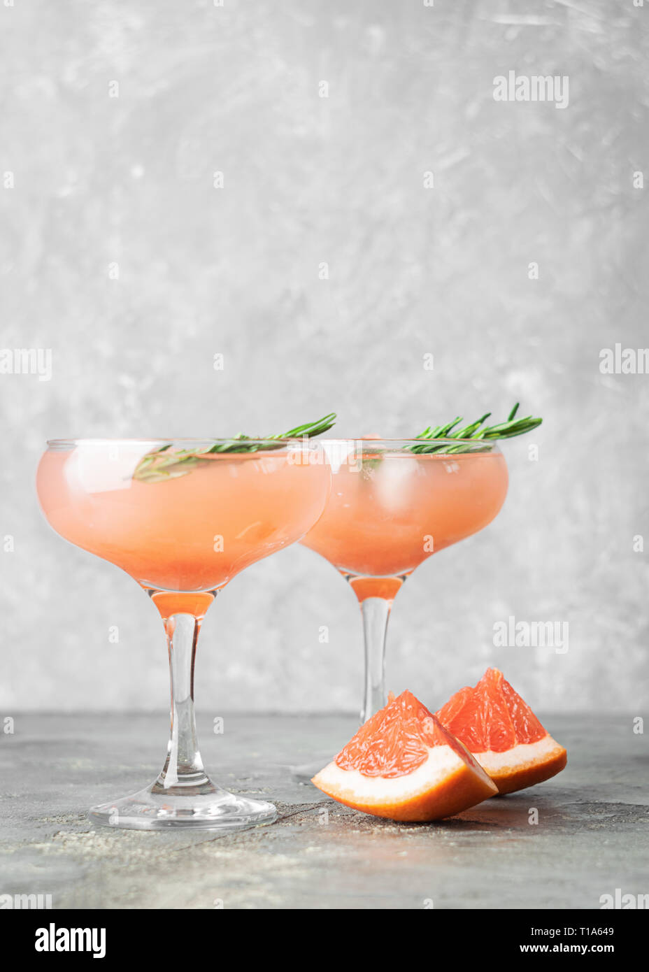 Drink grapefruit rosemary and ice two elegant glass goblets on gray ...