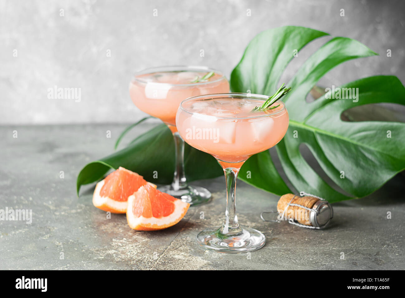 Drink grapefruit rosemary and ice in two elegant glass goblets on gray ...