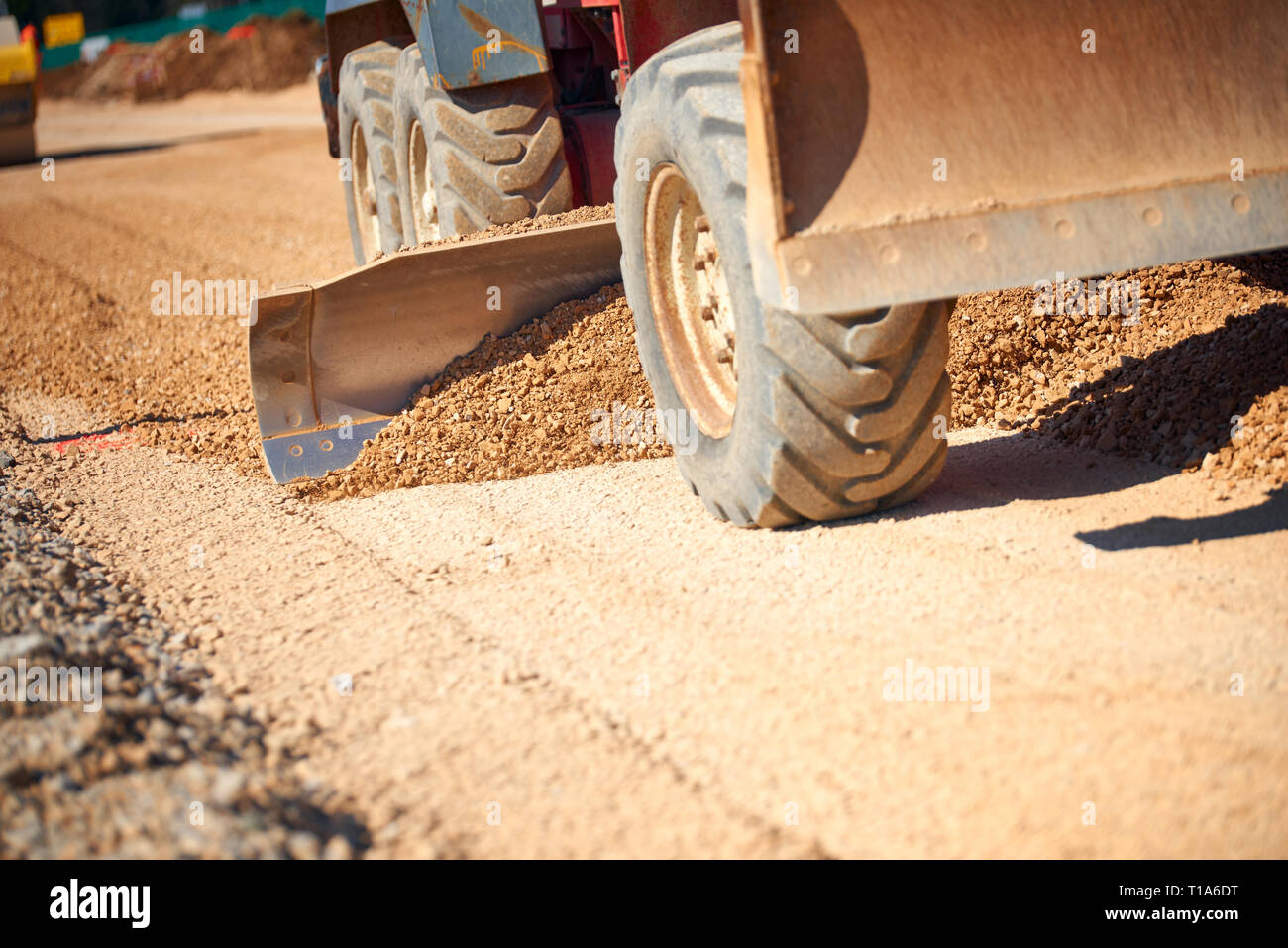 Road Grader Spreading Gravel On road Construction Site Closeup view