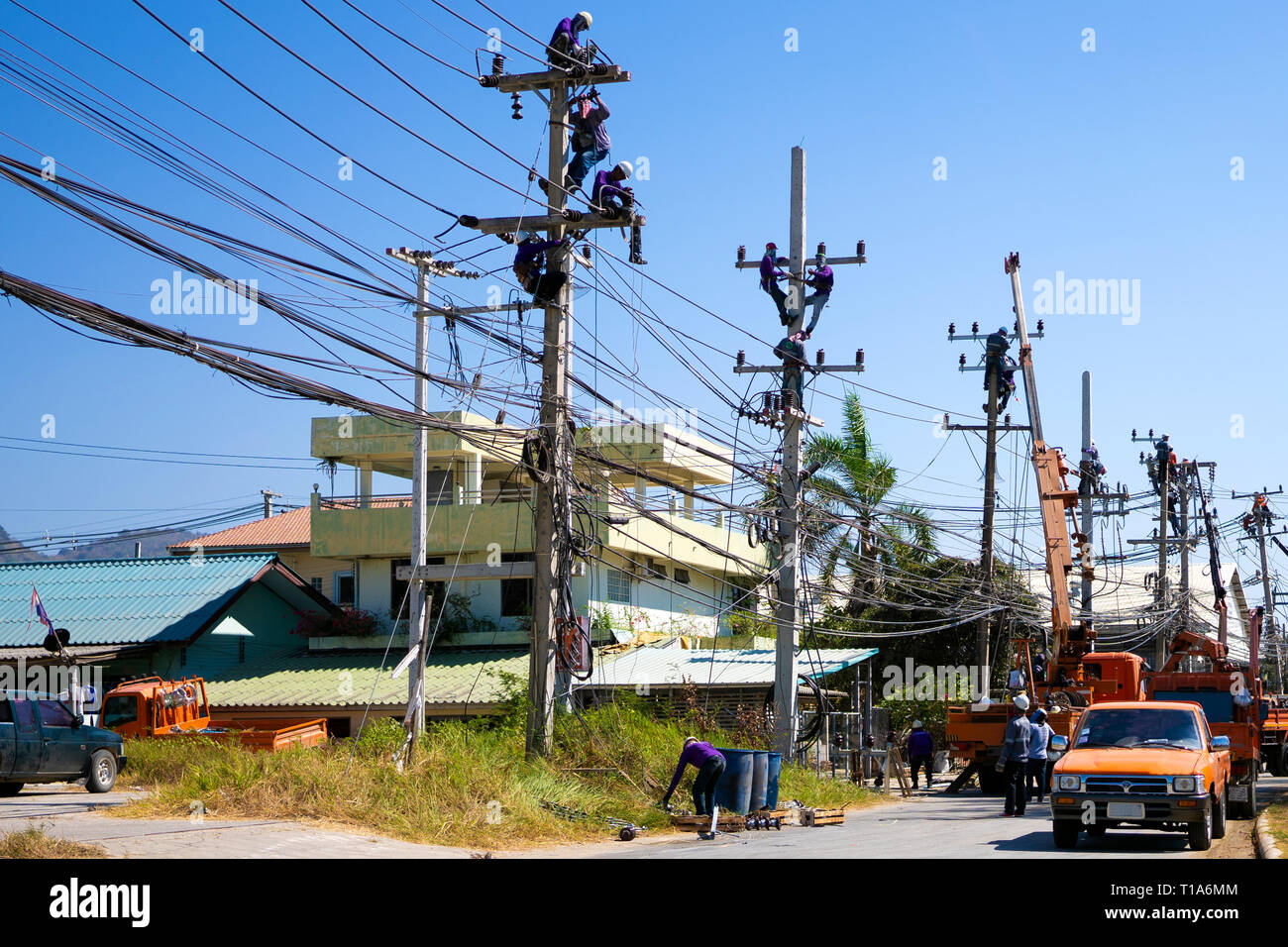 Electricians working on a power pole, filled with complex communication lines.  Stock Photo