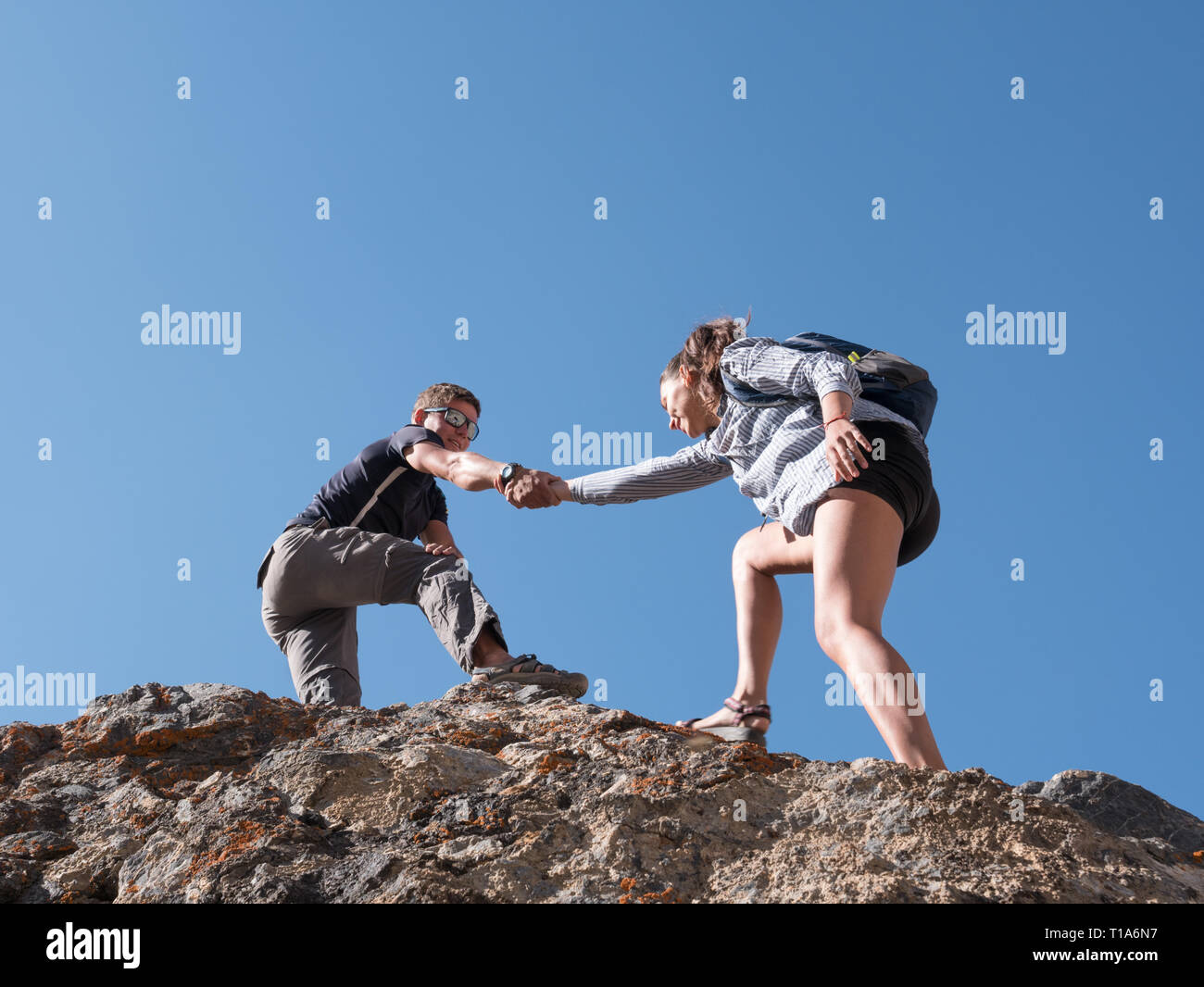 Helping hand couple hikers in mountains Stock Photo