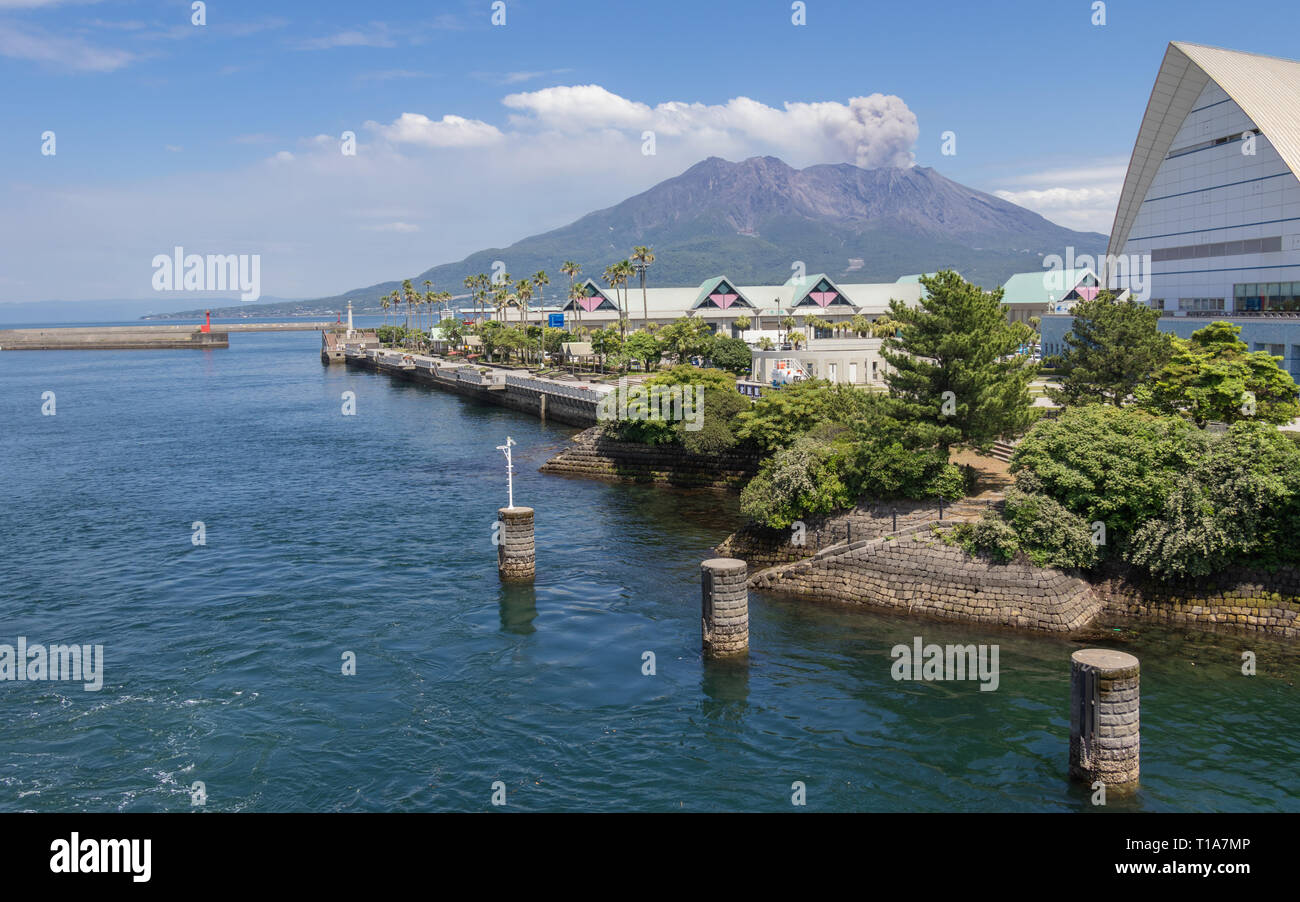 Entrance of Harbor Kagoshima with Sakurajima Port and Aquarium, the erupted Vulcan in the background. Taken from the Ferry. Kagoshima, Kyushu, Japan. Stock Photo