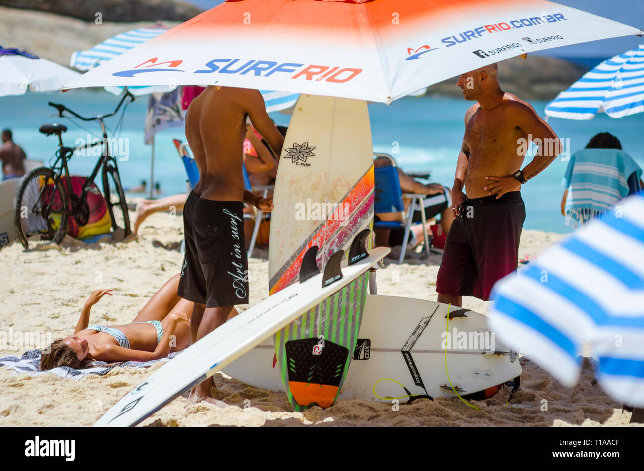 RIO DE JANEIRO - FEBRUARY 9, 2017: Young Brazilian surfers prepare their surfboards for a day of rentals at the Arpoador surf break on Ipanema Beach. Stock Photo
