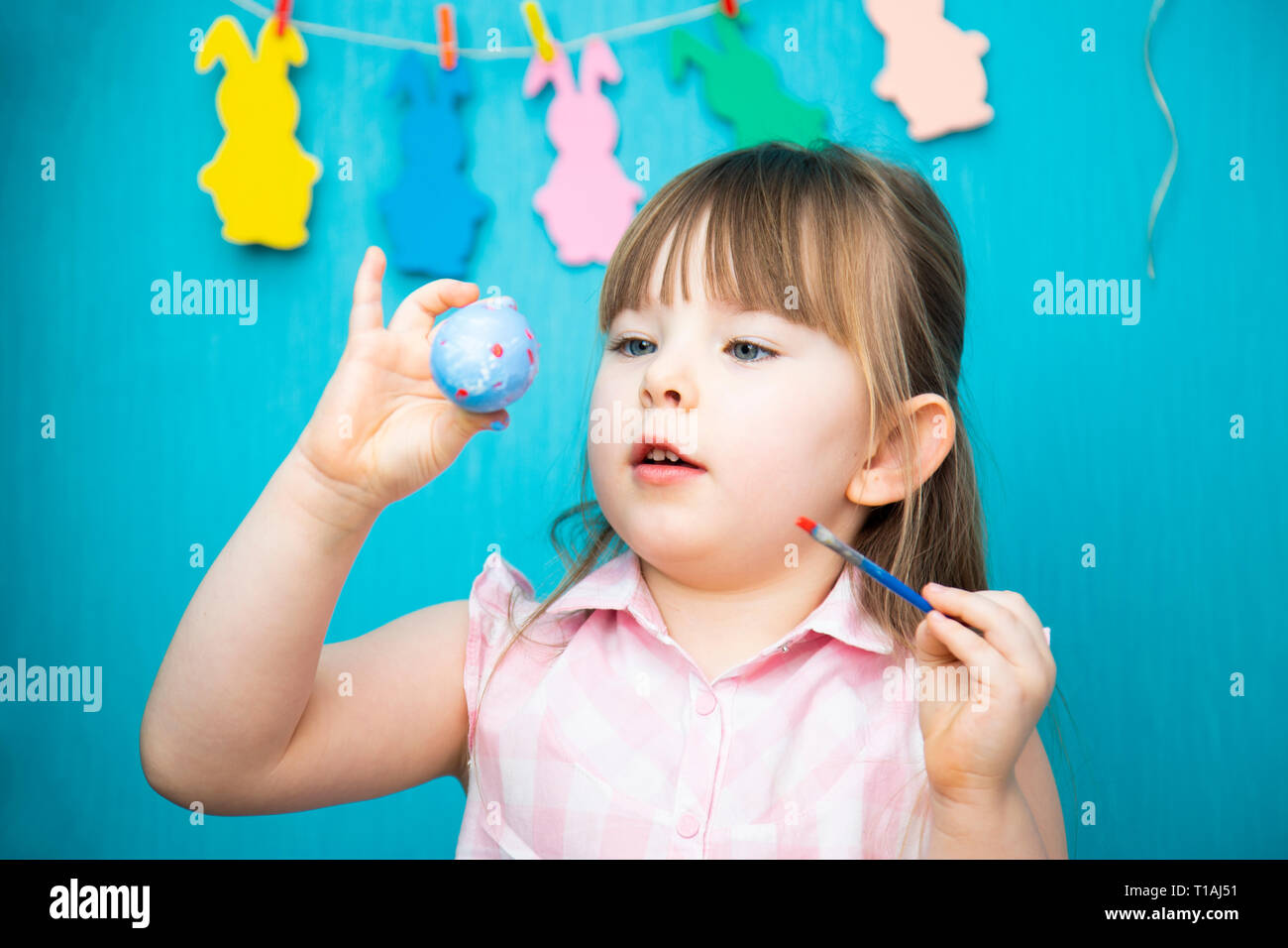 Cute smiling little girl painting colorful easter eggs Stock Photo
