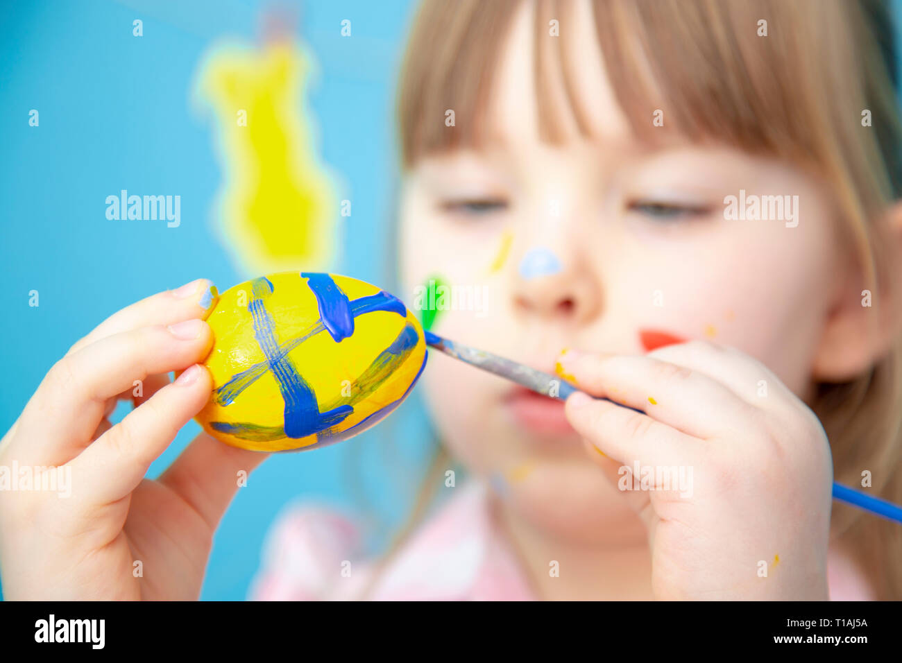 Cute smiling little girl painting colorful easter eggs Selected focus Stock Photo