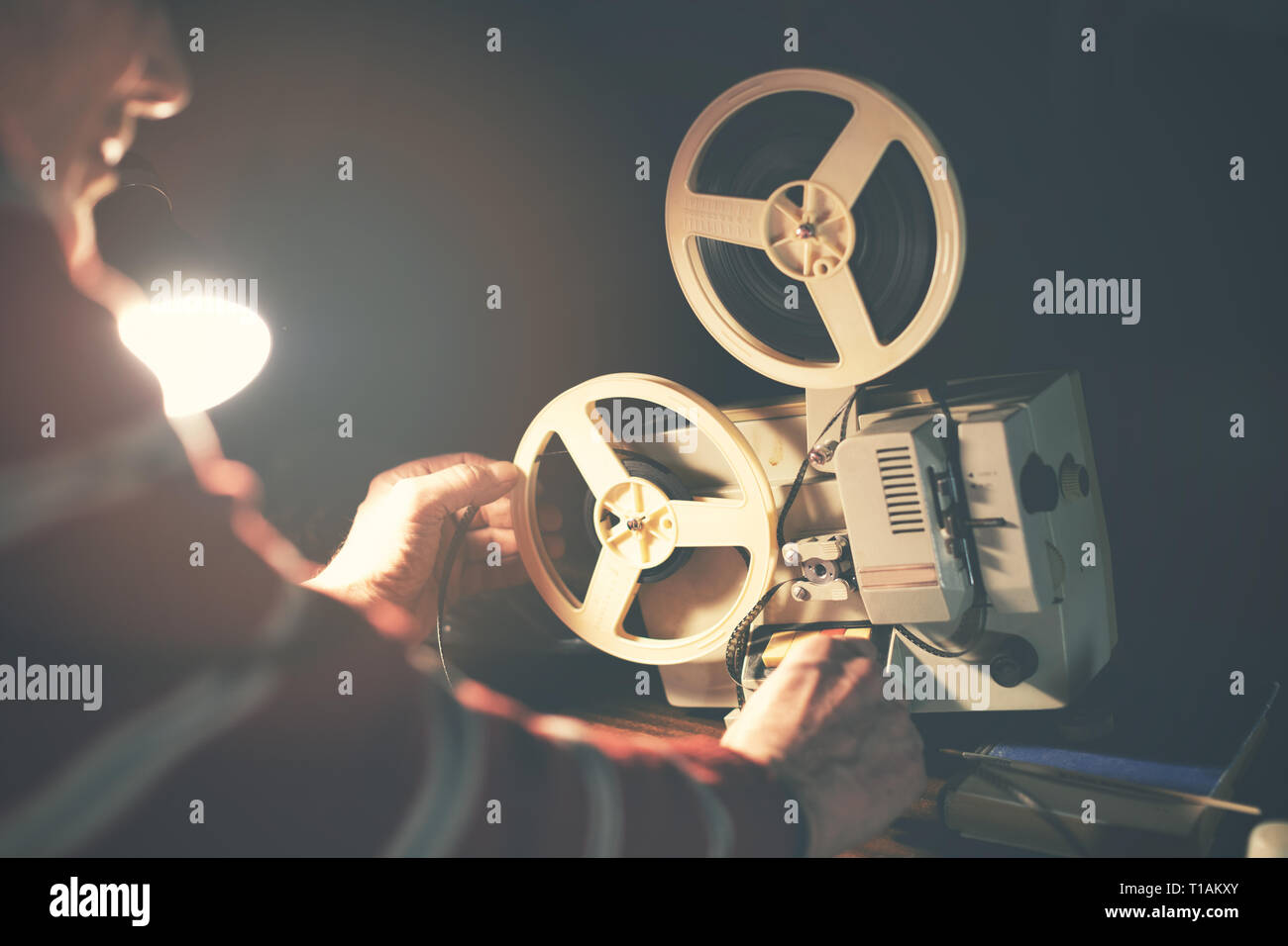 https://c8.alamy.com/comp/T1AKXY/man-set-up-film-reel-on-vintage-8mm-movie-projector-in-dark-room-T1AKXY.jpg