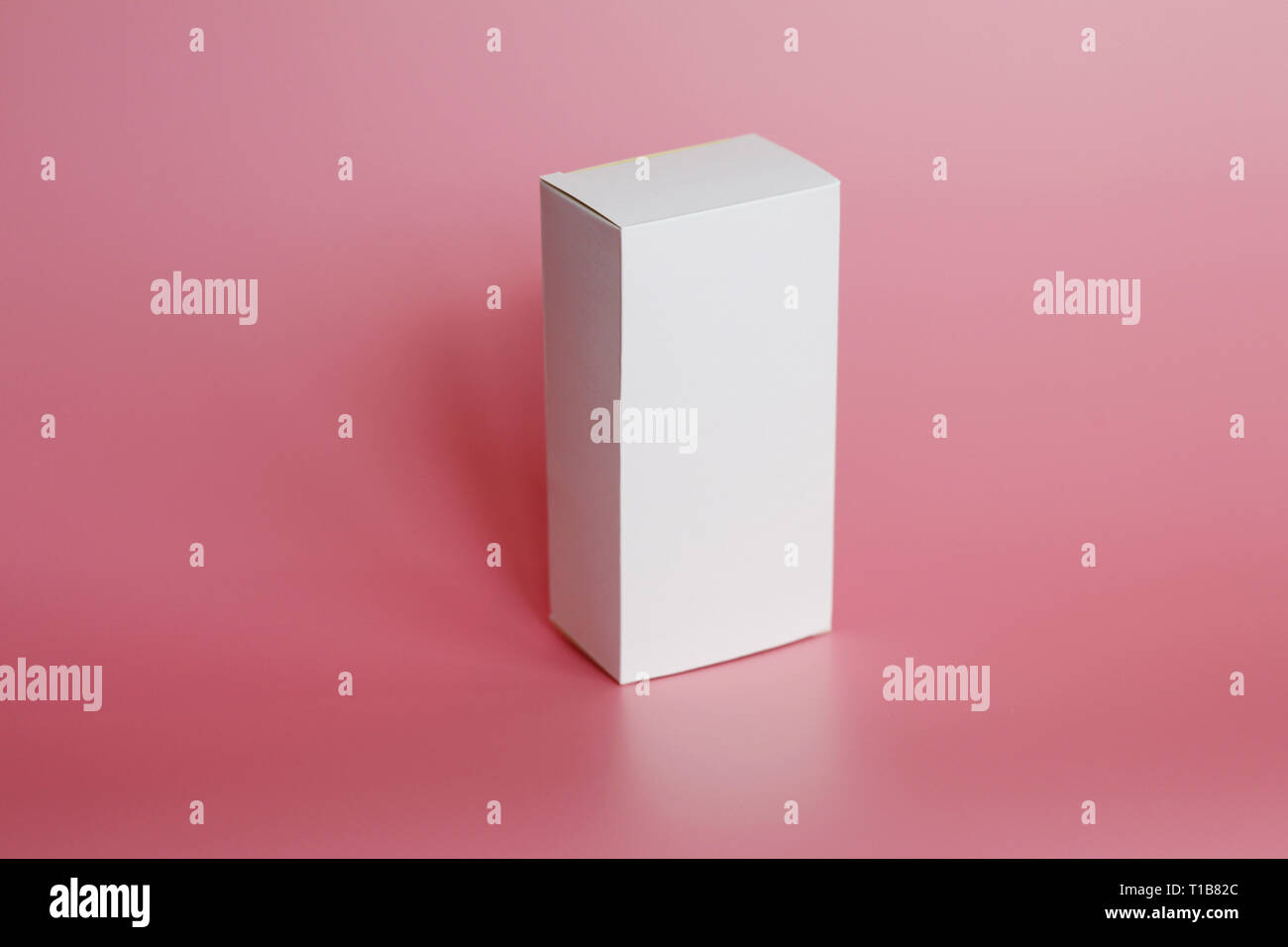 White box stands on a pink background. Vertical white box. Pink background. Box without labels. There are no labels on the package. Stock Photo