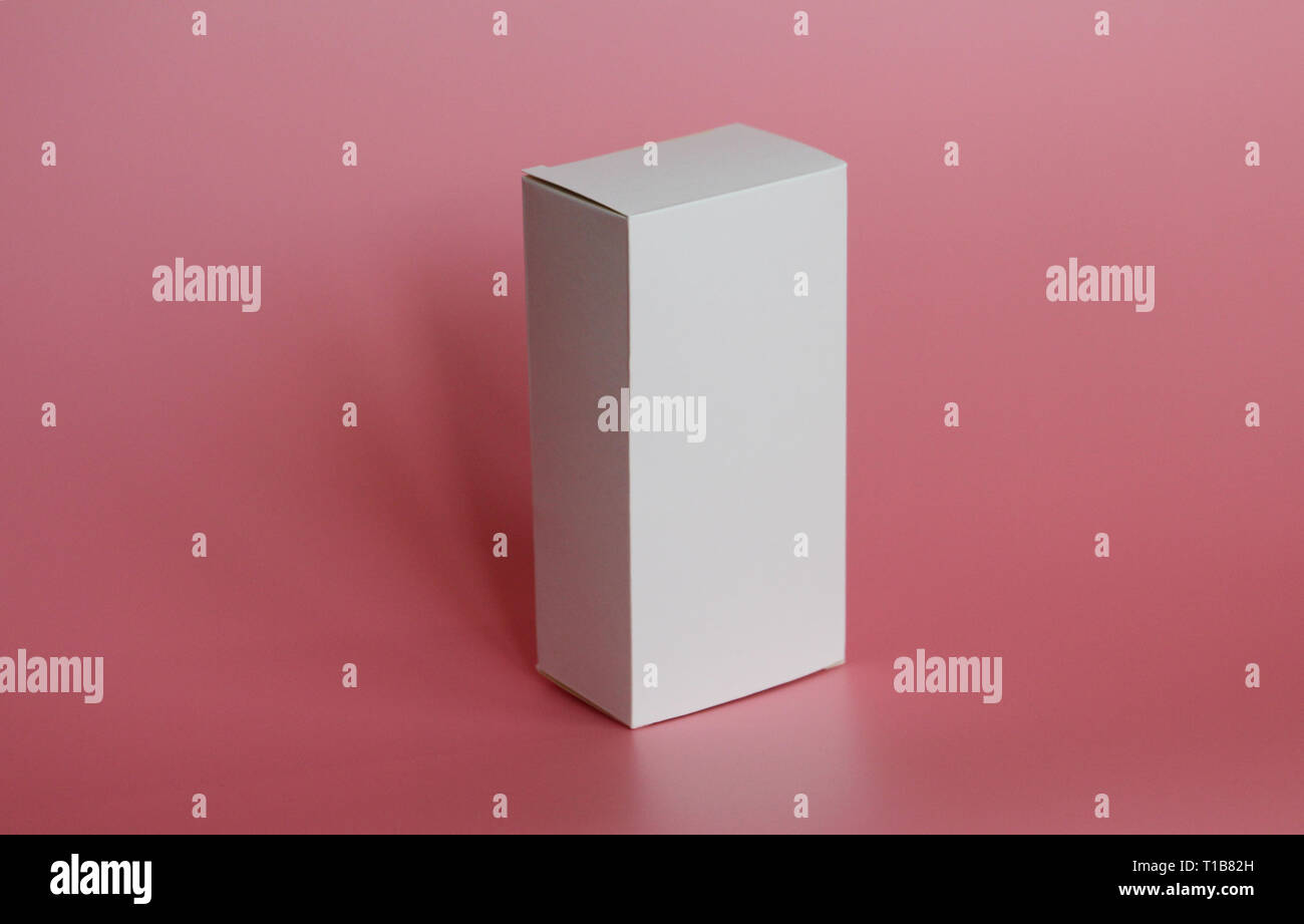 White box stands on a pink background. Vertical white box. Pink background. Box without labels. There are no labels on the package. Stock Photo