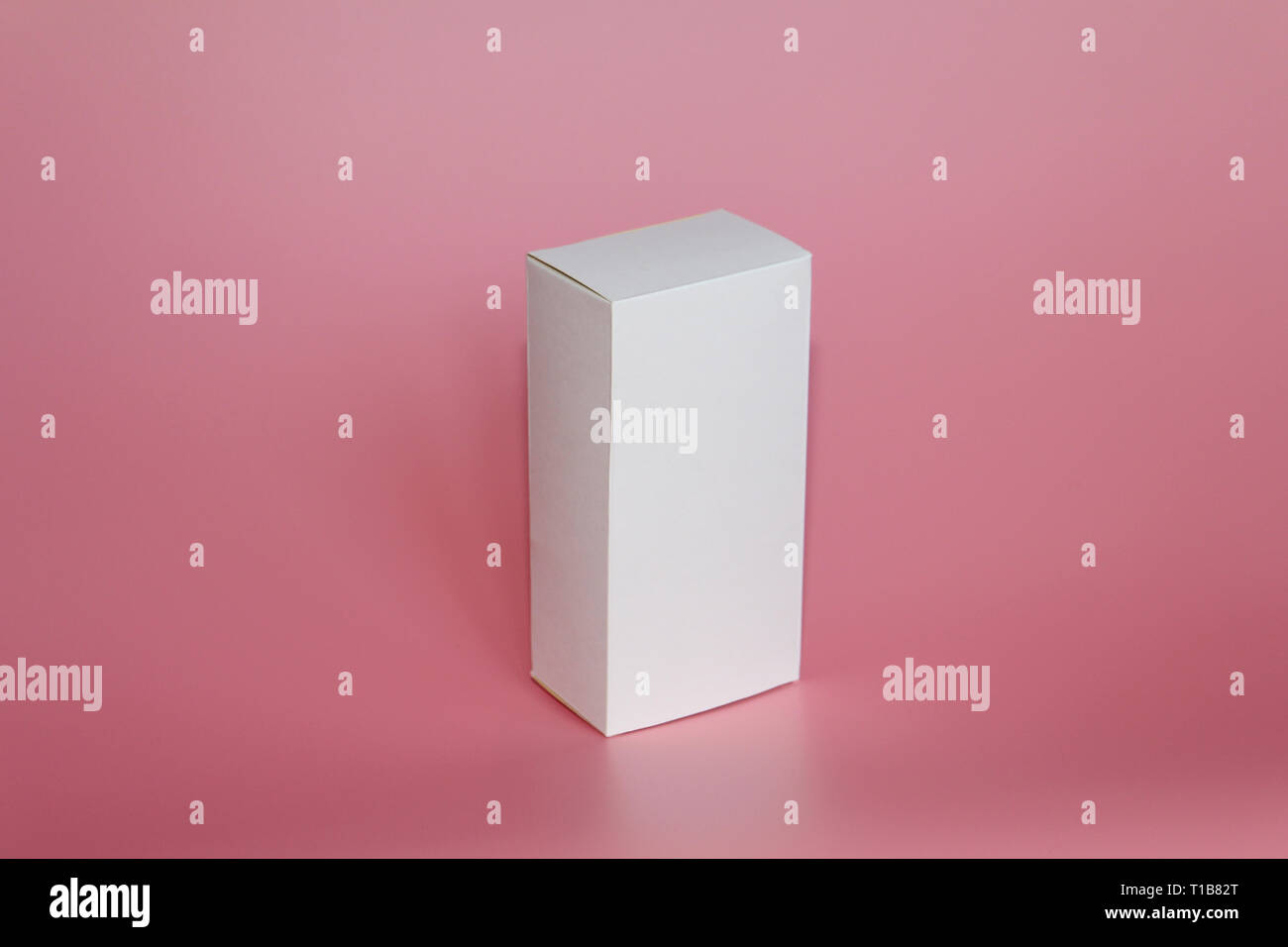 White box stands on a pink background. Vertical white box. Pink background. Box without labels. There are no labels on the package. Stock Photo