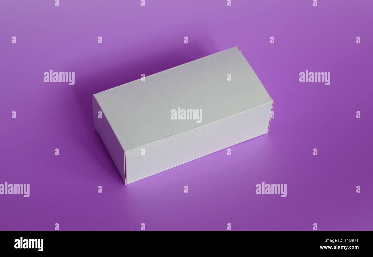 One white box on a purple background. Violet background. Box without labels. There are no labels on the package. Stock Photo