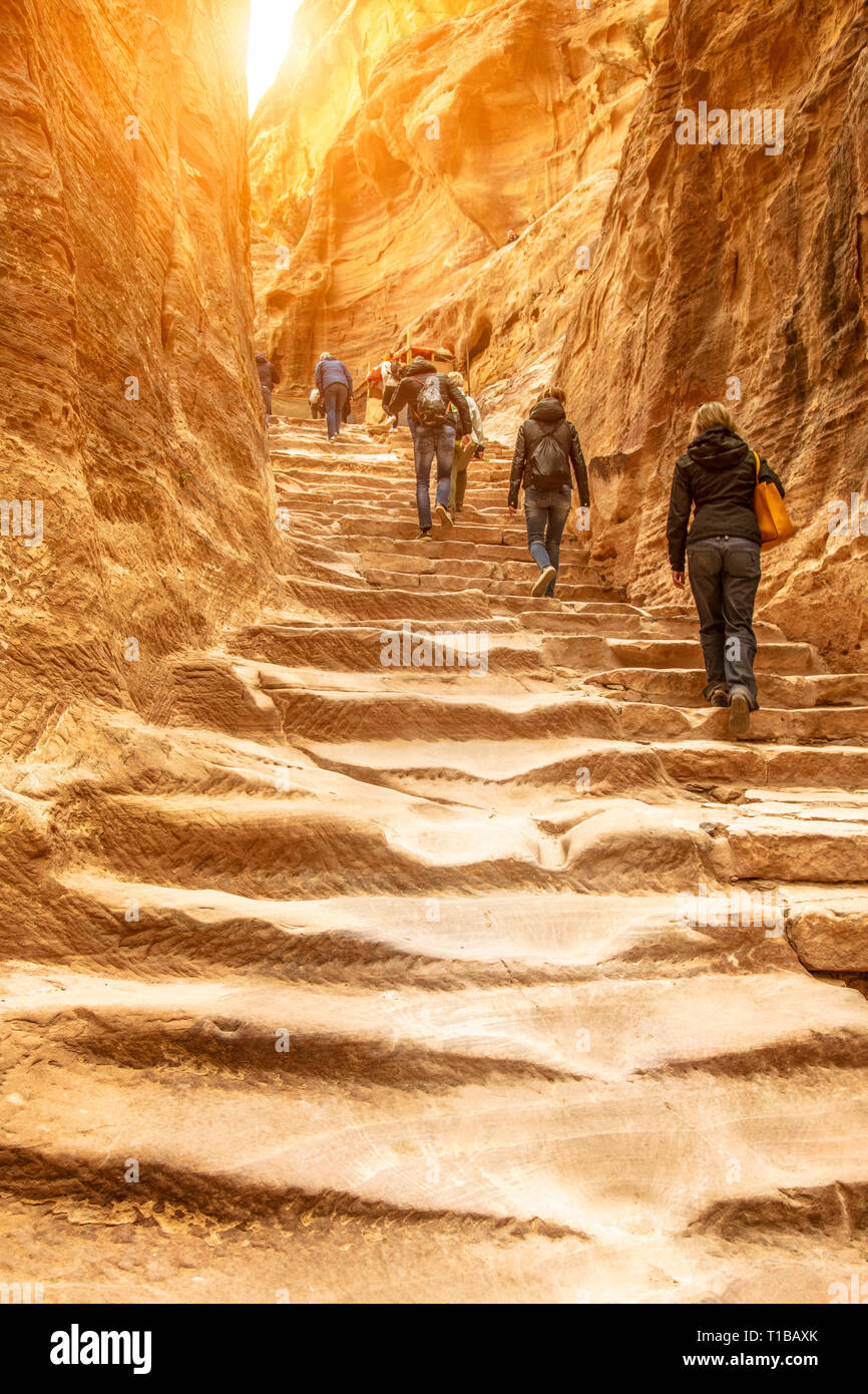 Travelers and tourists climb the impressive staircase carved into the rock that leads to the monastery of Petra. Jordan. Stock Photo