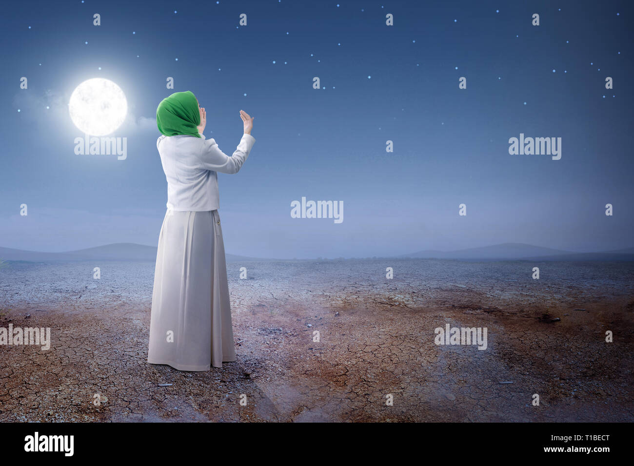 Rear view of asian muslim woman in veil raised hands and praying on the ...