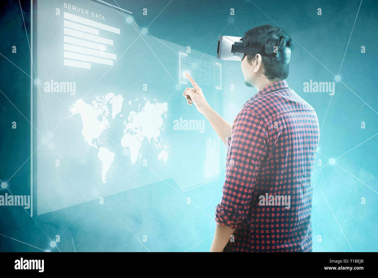 Rear view of asian man touching binary code on digital interface with virtual reality device display the world map, graphic bar and binary code. Augme Stock Photo