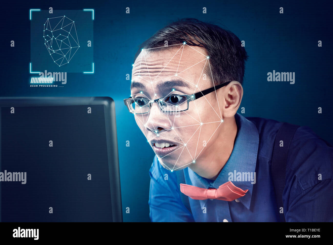 Attractive asian businessman with laptop using face recognition over blue background. Modern technology concept Stock Photo
