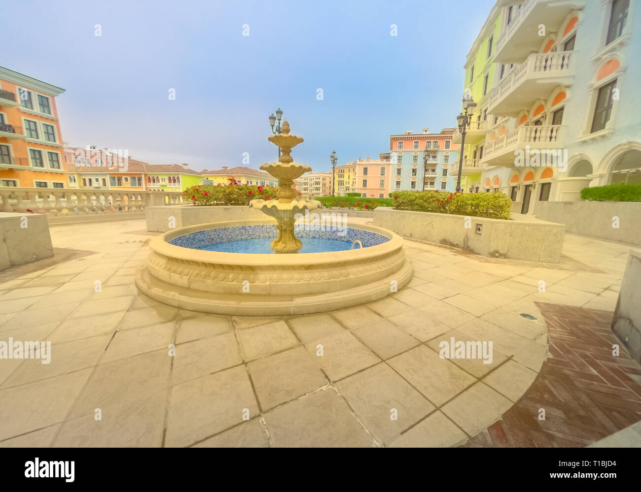 Fountain at little Venice in venetian style. Colorful houses in picturesque Qanat Quartier icon of Doha, Qatar at sunny day with blue sky. Venice at Stock Photo
