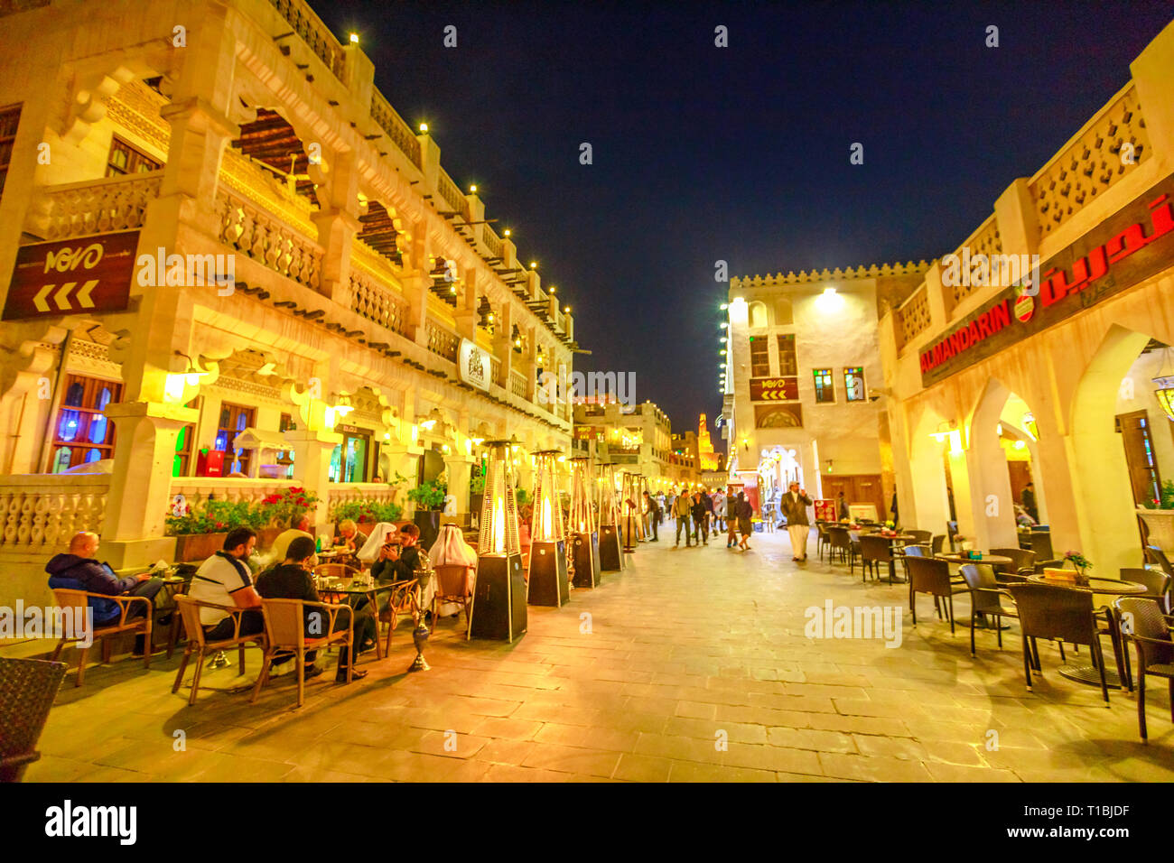 Doha, Qatar - February 17, 2019: tourists and locals in restaurants in Souq Waqif central street, the old traditional market in Doha. Night urban Stock Photo