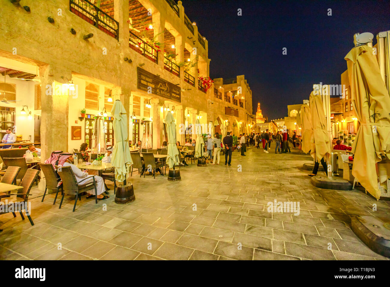 Doha, Qatar - February 17, 2019: Street view in Souq Waqif market with cafes and restaurants and the Fanar Islamic Cultural Center with Spiral Mosque Stock Photo