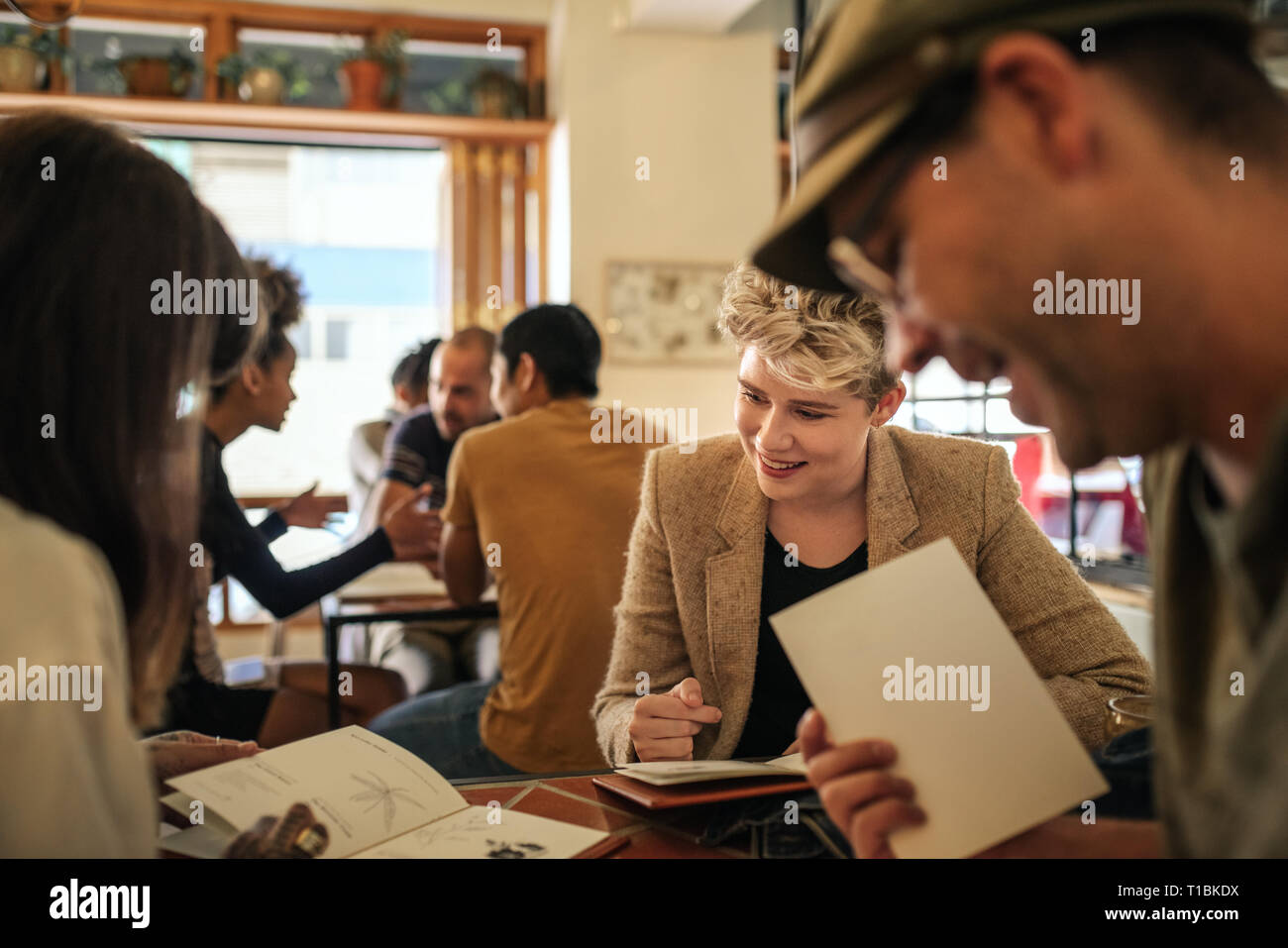 Smiling young friends reading menus in a bistro Stock Photo