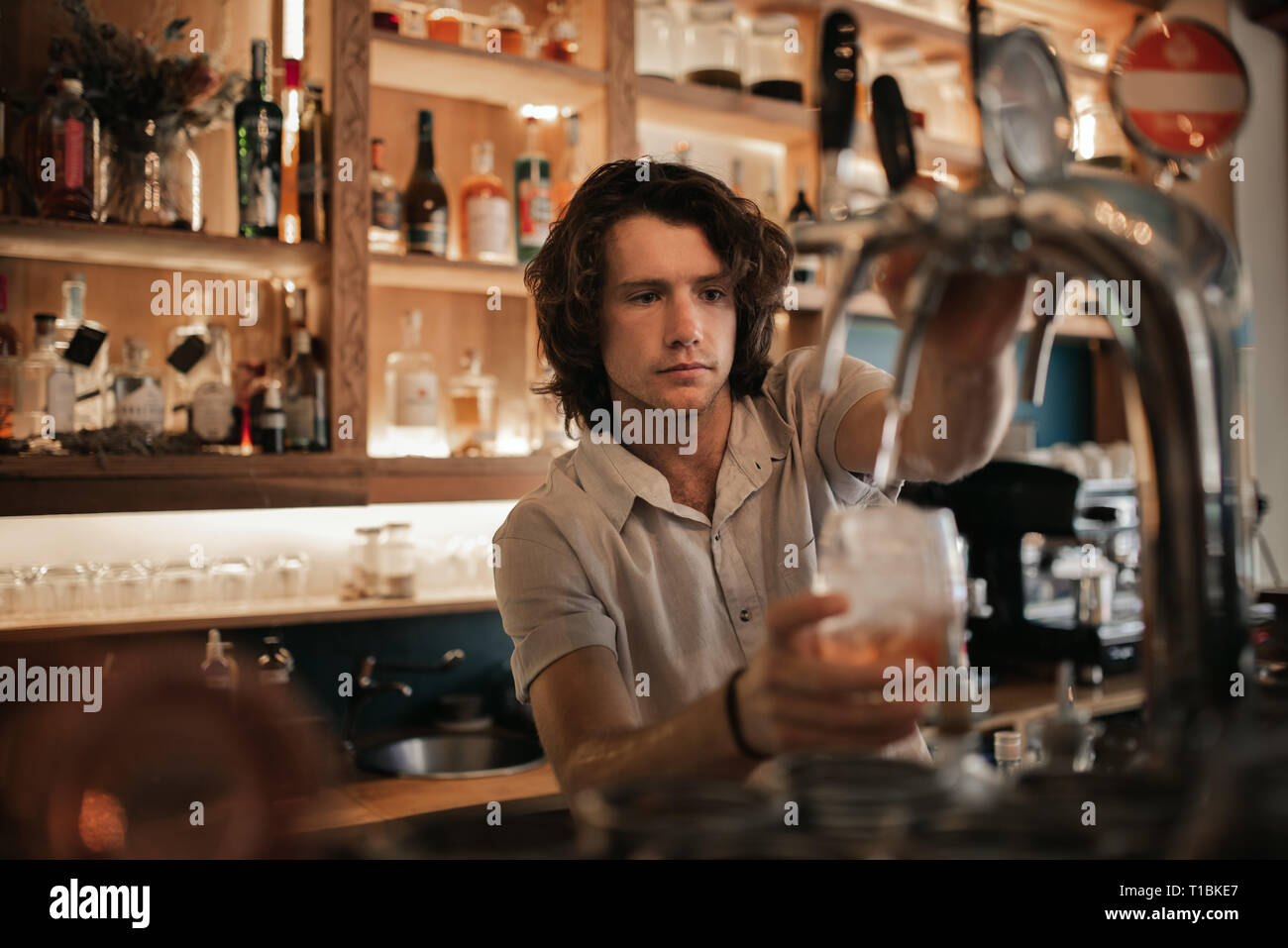Bartender preparing drinks behind a bar counter at night Stock Photo