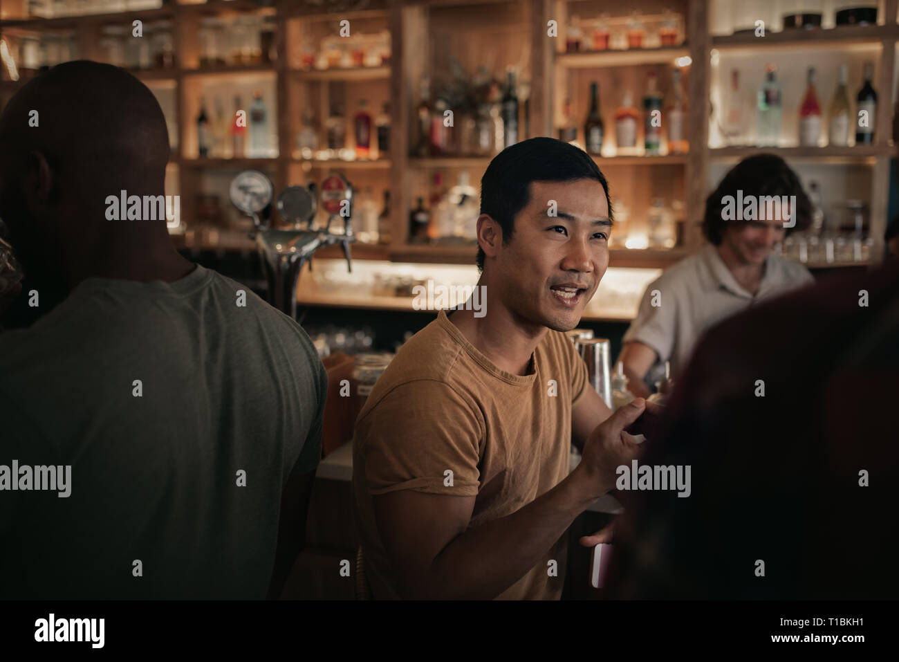 Young man talking with friends in a busy bar Stock Photo