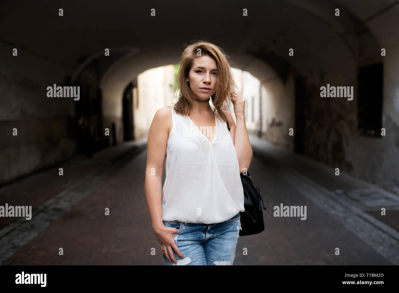 Portrait of posing beautiful young woman, with hand in her short  hair. Shadow in a tunnel as a interesting background. Stock Photo