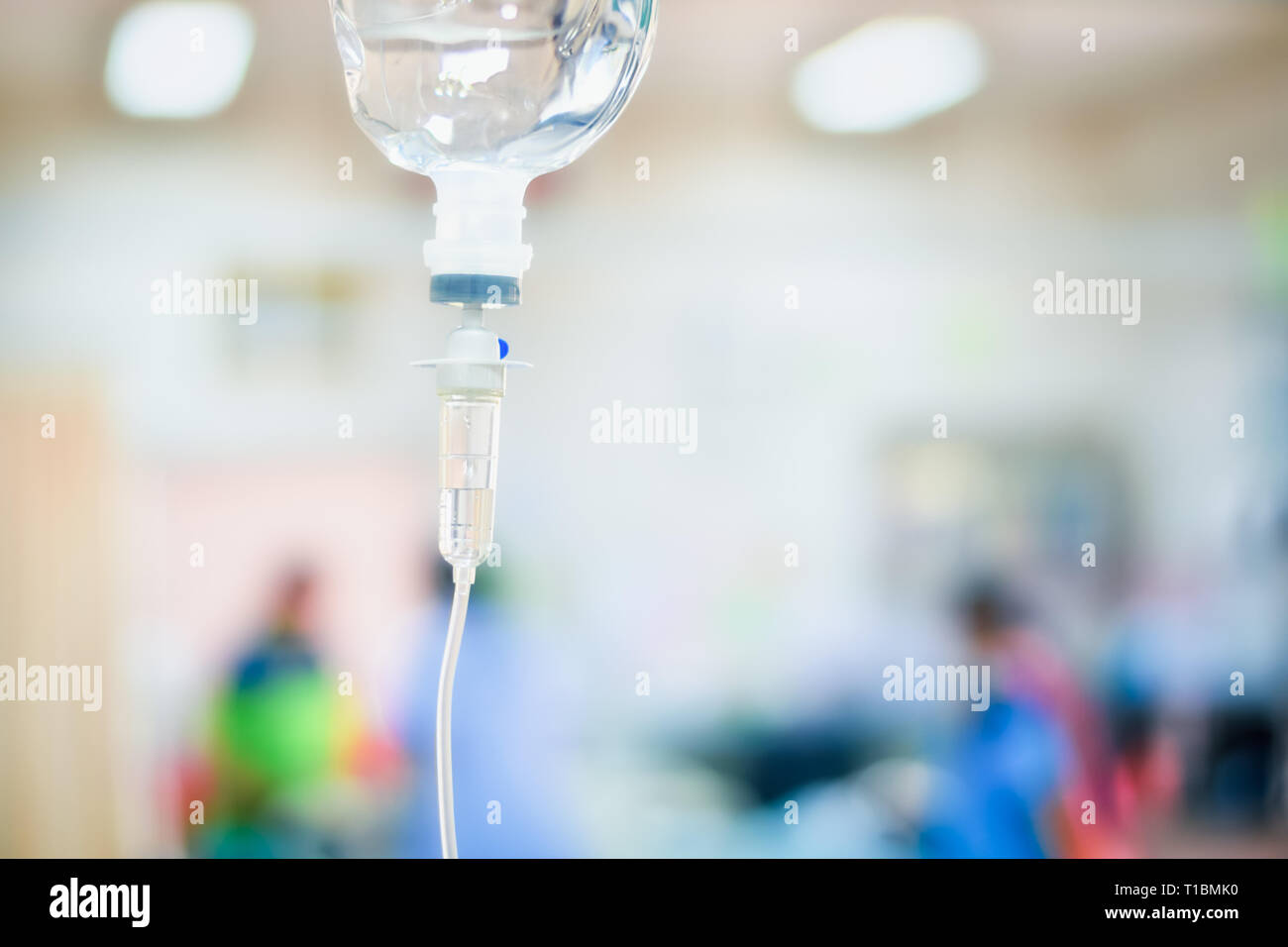 Close up saline IV drip for patient in hospital with copy space on n blurred doctor give medical and other attention to a sick person Stock Photo