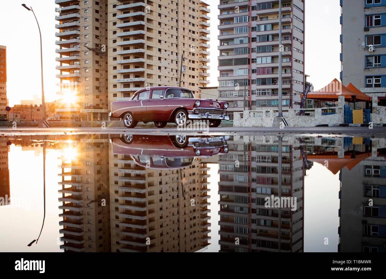 A vintage American car drives along the Malecon during sunrise in Havana, Cuba. Stock Photo