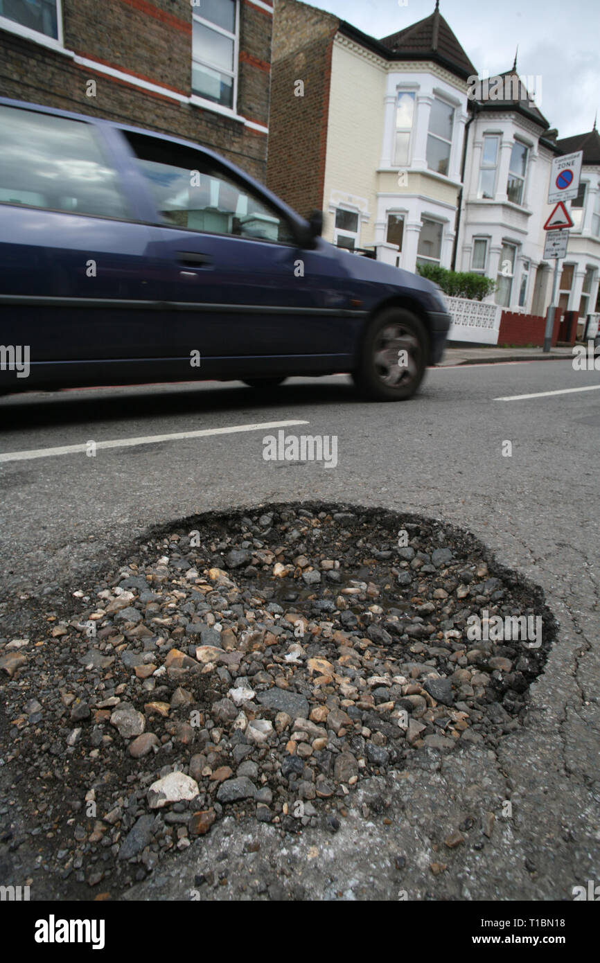 Embargoed to 0001 Tuesday March 26 A pothole in a road in Tooting, SW London. The annual local authority road maintenance survey found some 1.86 million potholes were filled in during 2018/19 compared with 1.53 million during the previous 12 months, the highway maintenance budgets have increased from an average of £20.6 million to £24.5 million year-on-year. Stock Photo