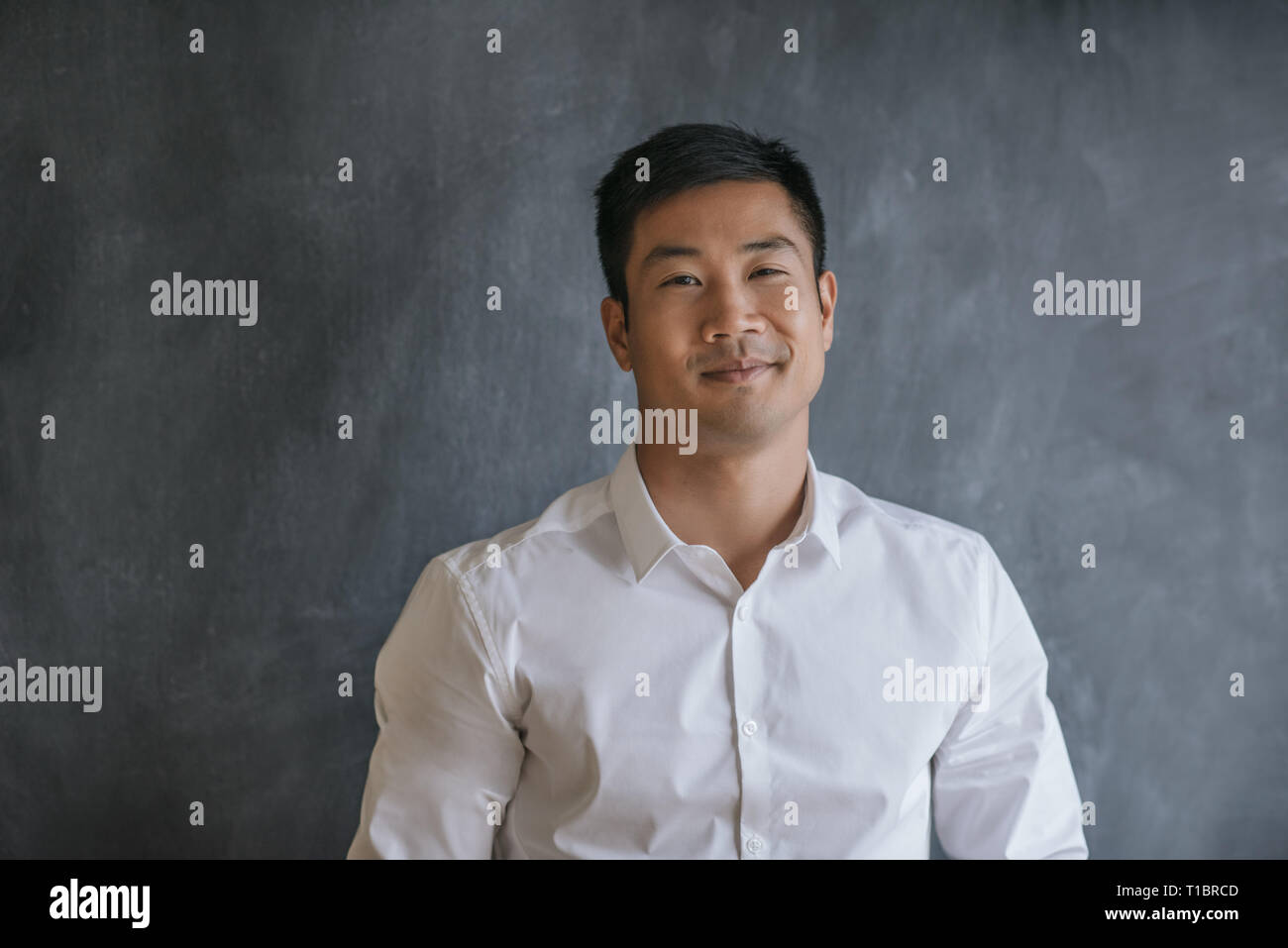 Asian businessman smiling while standing in front of a chalkboard Stock Photo